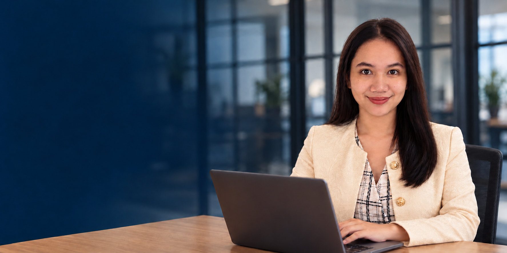 Portrait of Allyssa Tiburcio in a cream jacket at a laptop.